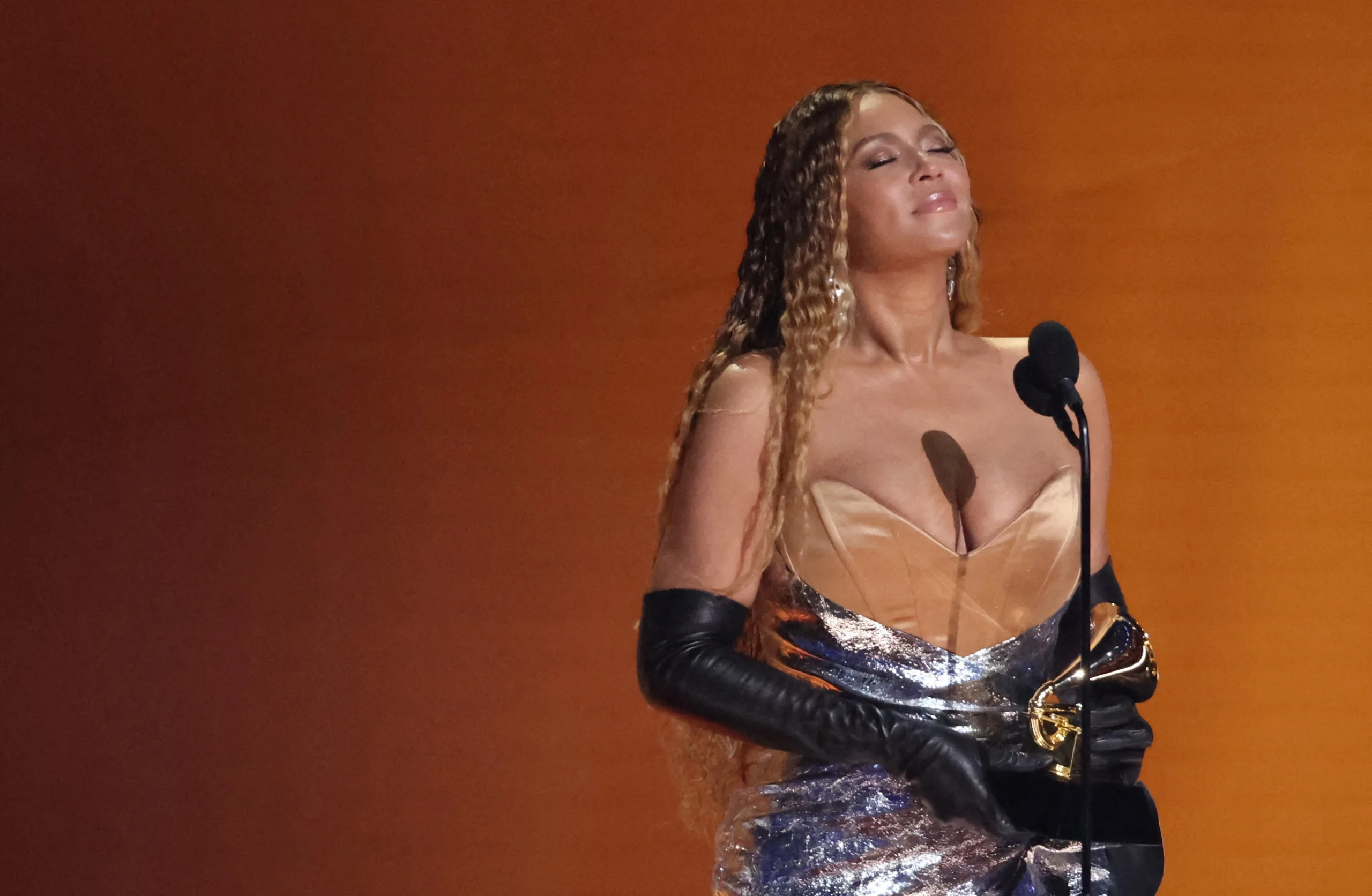Beyoncé holding a microphone with fans cheering in the background.