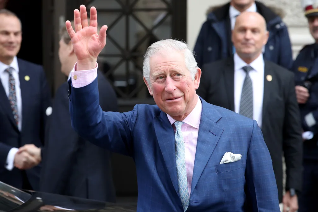 King Charles III with a concerned expression, surrounded by medical equipment and doctors.