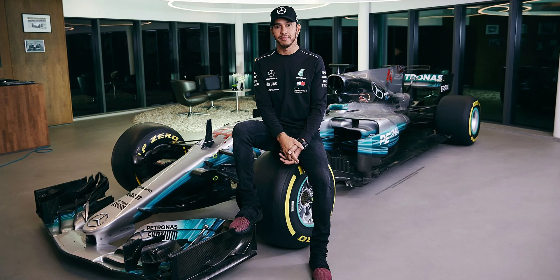 A collage of Lewis Hamilton in his racing suit, Mercedes logo, and Ferrari logo, symbolizing the sensational move of the seven-time Formula One champion from Mercedes to Ferrari for the 2025 season.